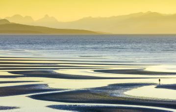 Sunset reflecting on tidal pools along Rathtrevor beach looking across the Salish sea to the coastal mountains from Parksville Vancouver Island British Columbia