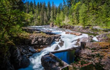 River with whitecapped waves running through rocky shoreline between forested hills Cowichan River Vancouver Island BC Canada