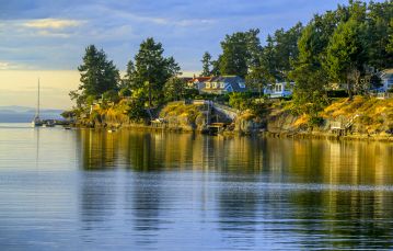 Calm blue ocean waters in front of homes on the shoreline in Parksville Vancouver Island British Columbia.