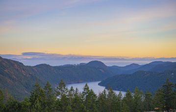 Beautiful vista with trees in foreground with ocean mountains and sunset skyline in background on southern Vancouver Island BC.