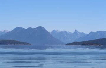 Serene blue ocean set against mountain range and clear blue skies near southern Vancouver Island