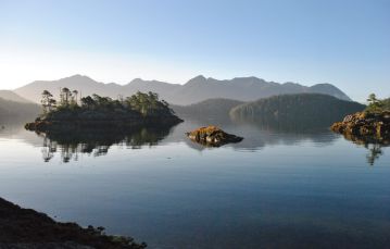 Calm ocean waters around small islands with mountain backdrop near Gold River in central Vancouver Island British Columbia Canada