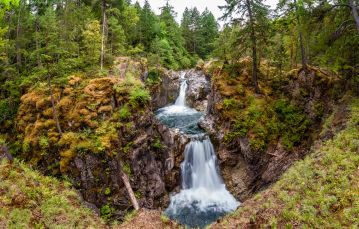 Waterfall flowing through forested rocky shoreline near Qualicum Beach and Parksville on Vancouver Island British Columbia Canada