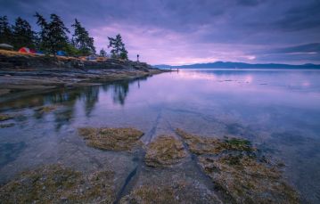 Camping at Ruckle Provincial Park on Saltspring Island with tents set against shoreline during sunset.